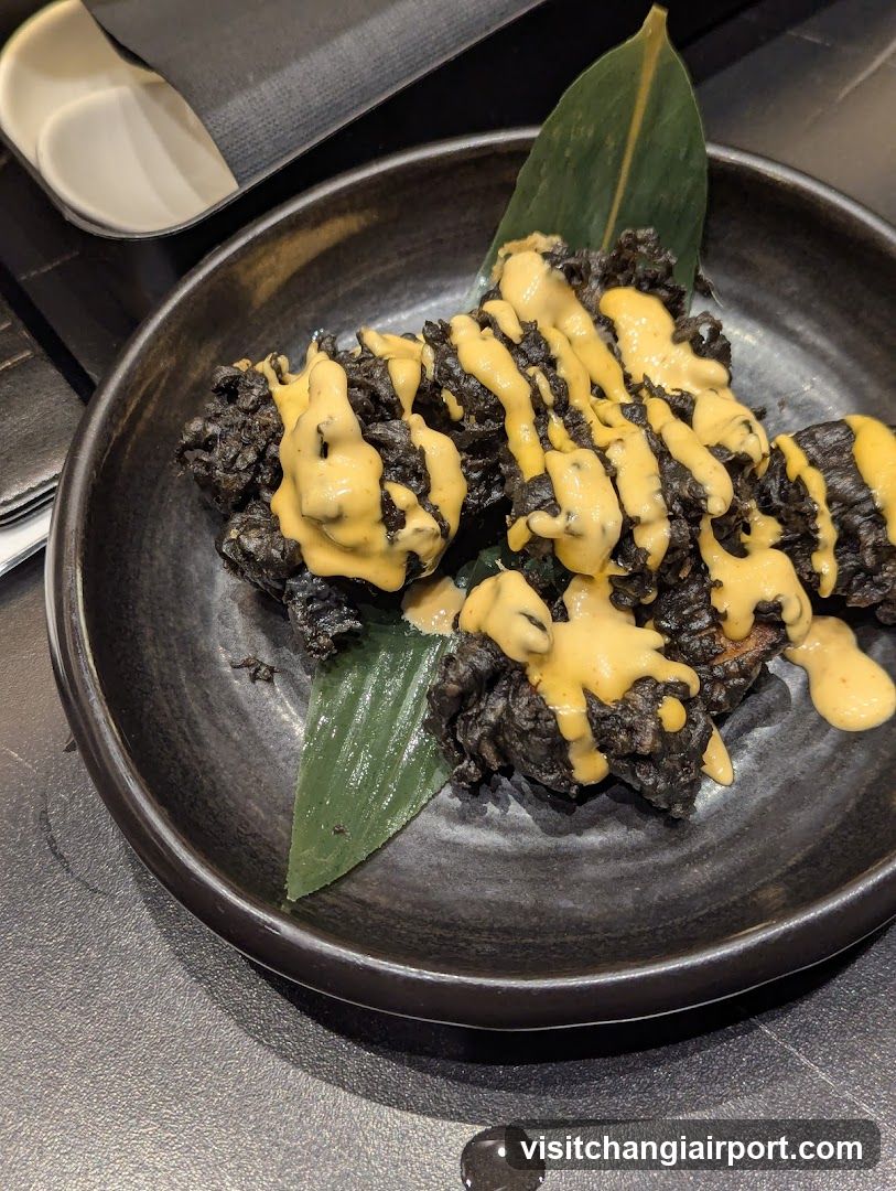 Black food with yellow sauce on a dark plate
