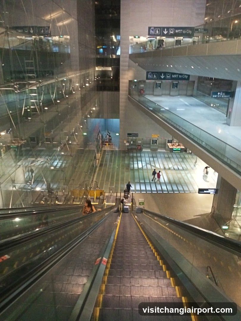 View from escalator looking up at MRT station interior with signage indicating 'MRT to City' and multiple levels of walkways.