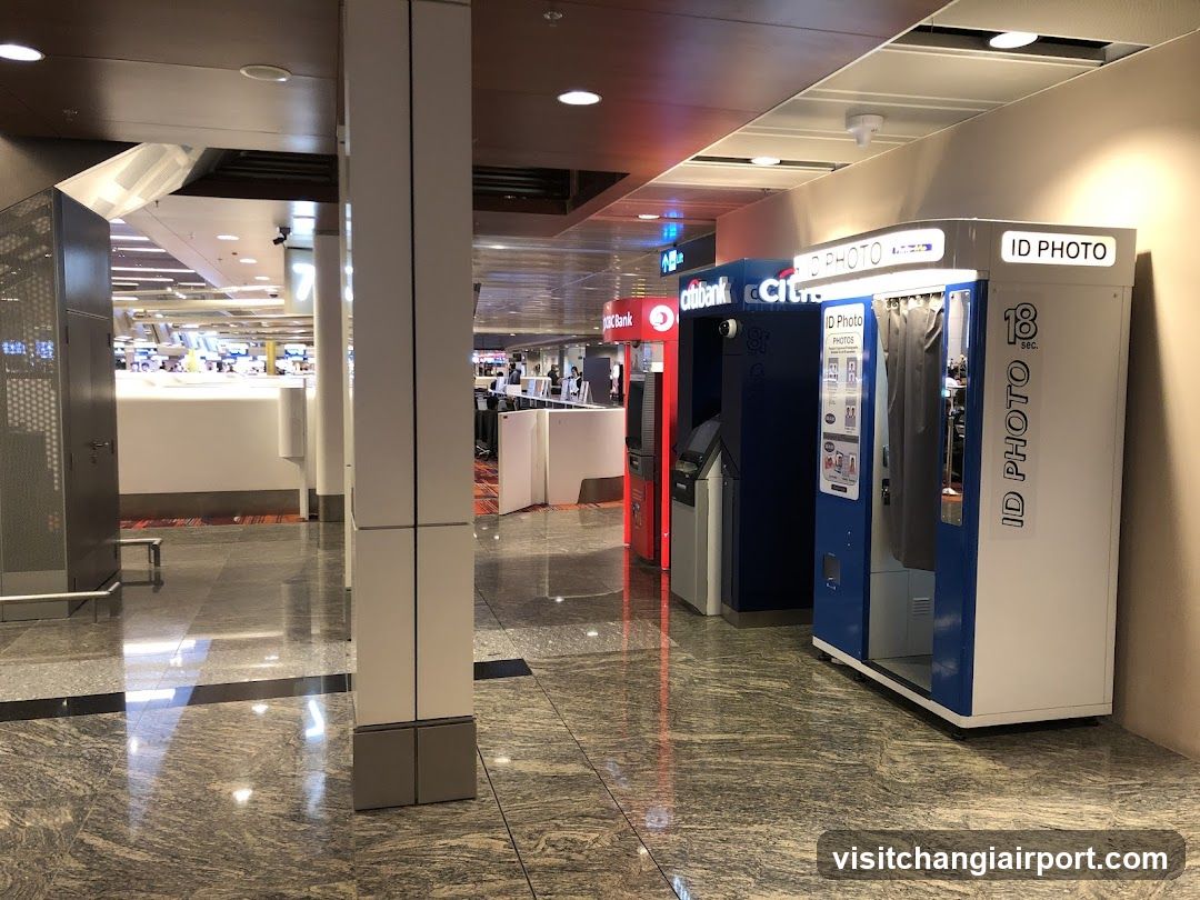 The image shows an indoor area with a shiny marble floor, featuring several automated kiosks including ID photo booths and ATMs from Citibank. The background reveals a spacious hall with more counters and possibly a food court or service area.