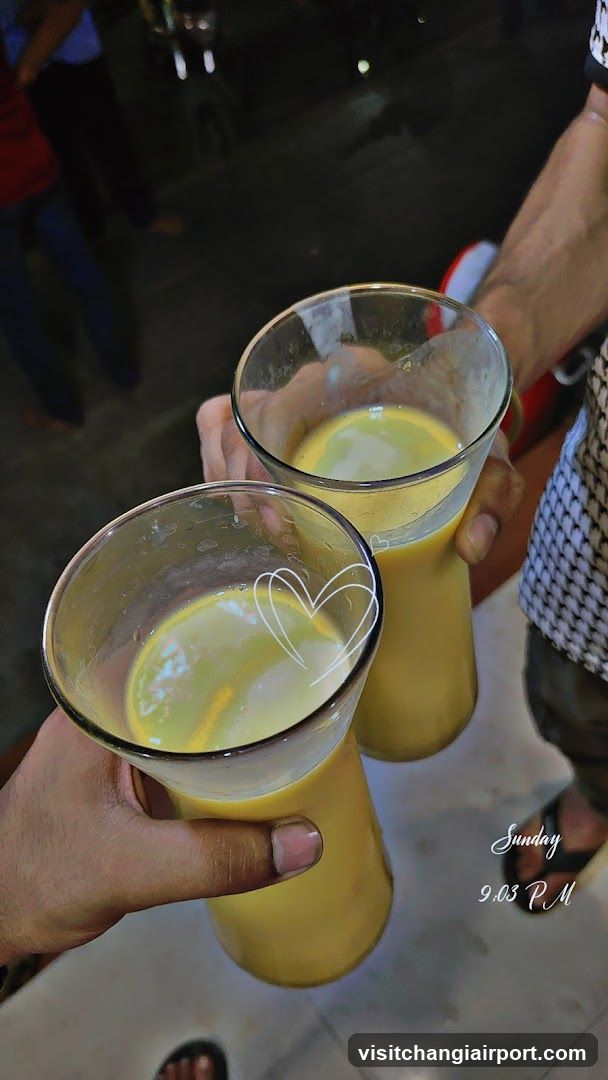 Two glasses of yellow drink being held up