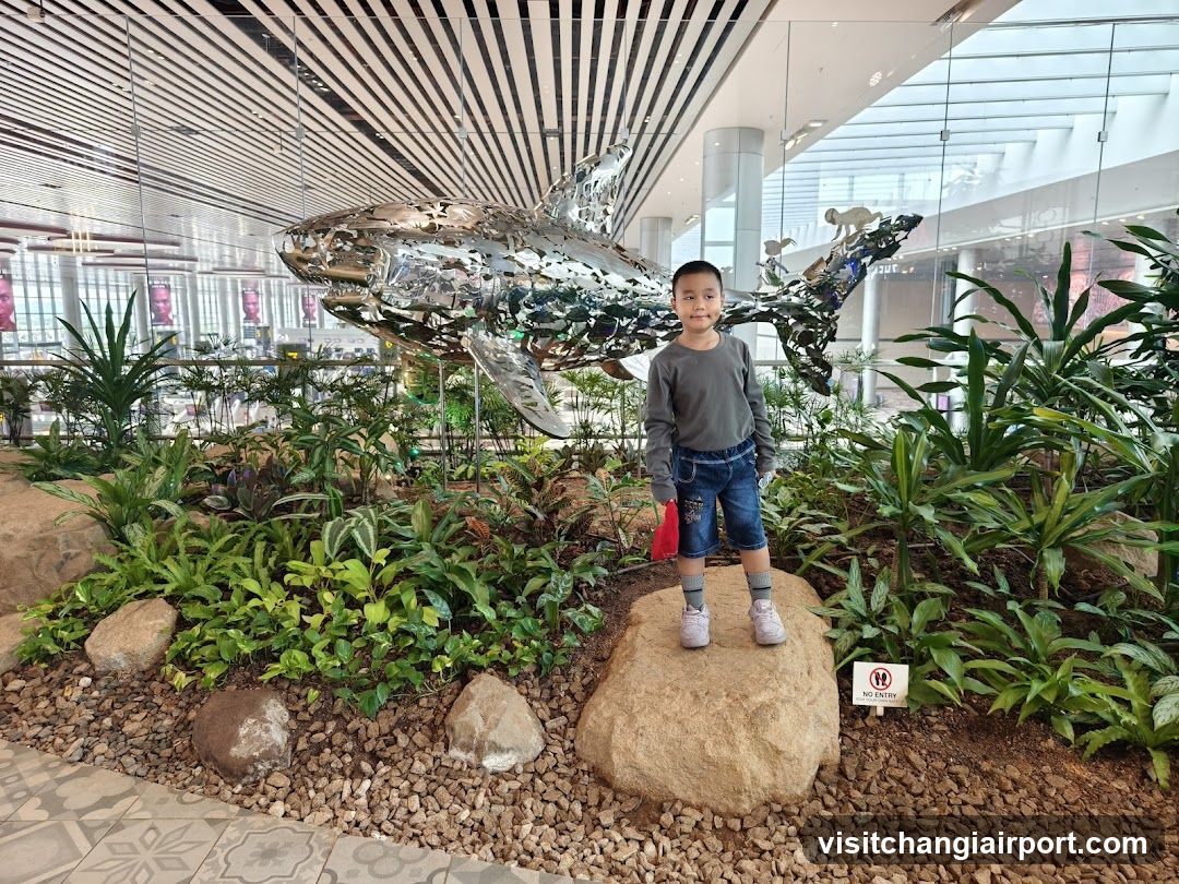 Boy with Shark Sculpture in Indoor Garden