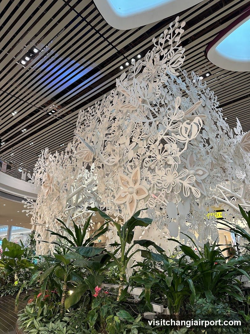 White floral sculpture display with greenery