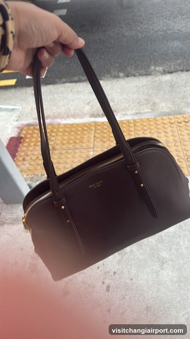 Hand holding a brown handbag