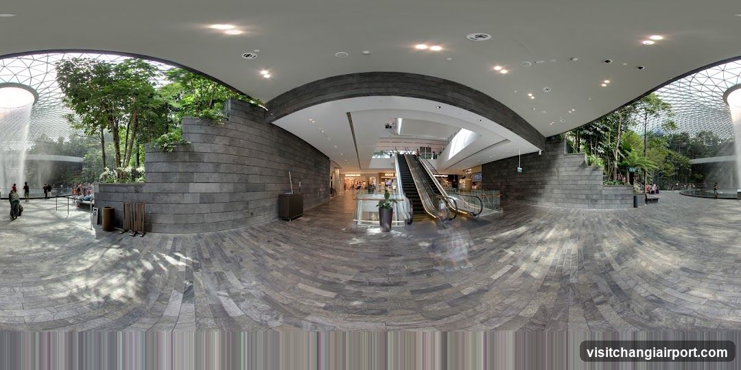 Interior of a modern shopping mall with escalators and greenery