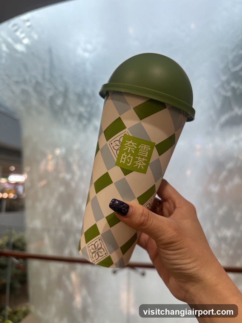 Hand holding a green and white checkered cup with Chinese characters