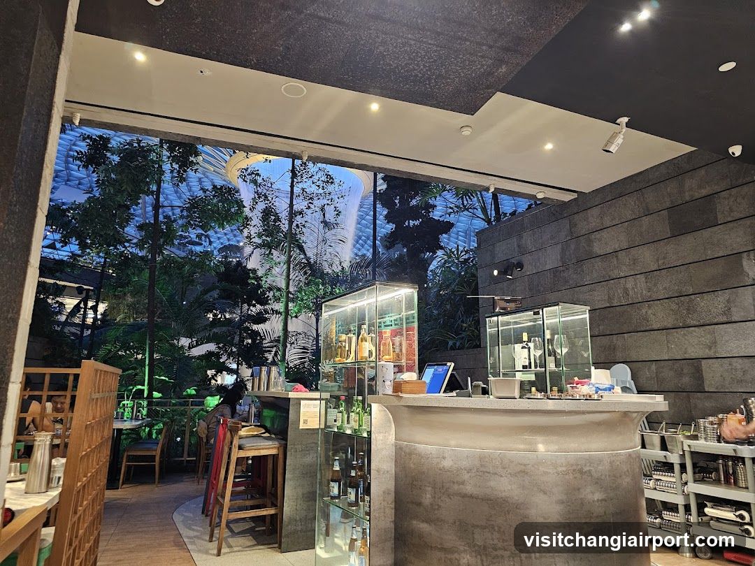 Interior of a modern bar or lounge with glass display cases and outdoor greenery view