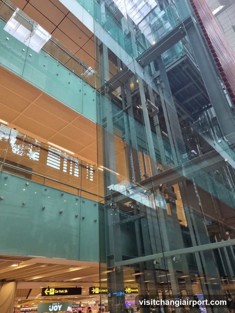 Interior of a modern building with glass elevators and signage