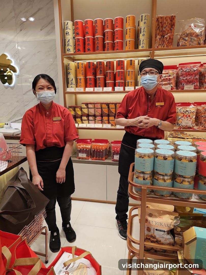 Staff in red uniforms standing in a shop with shelves of products