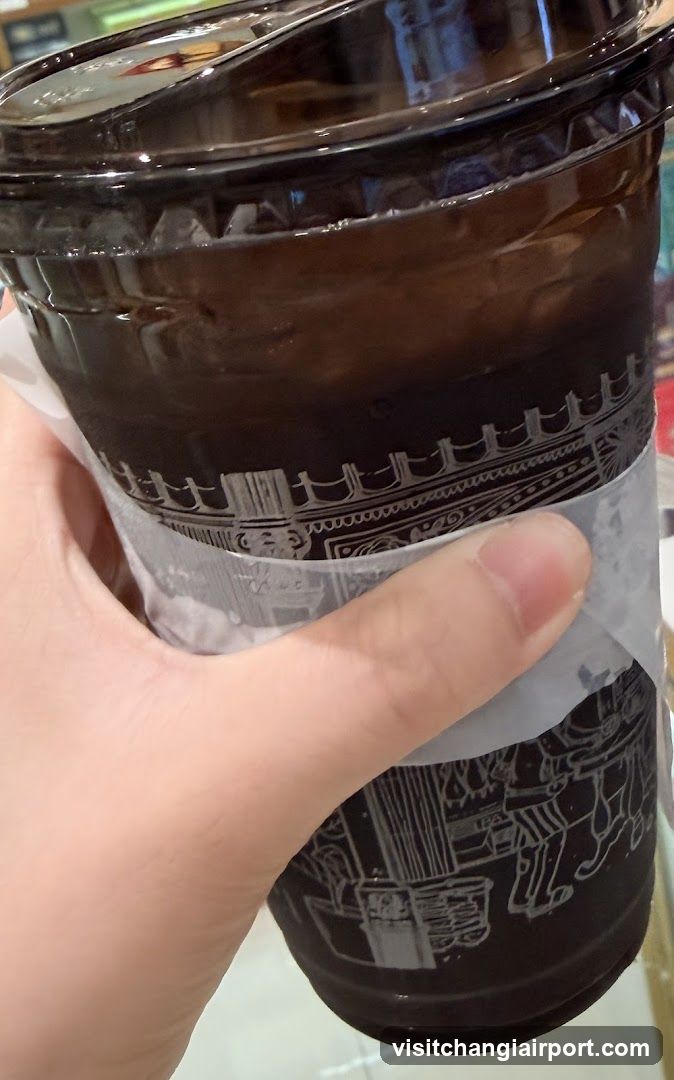 Hand holding a dark beverage cup with decorative pattern