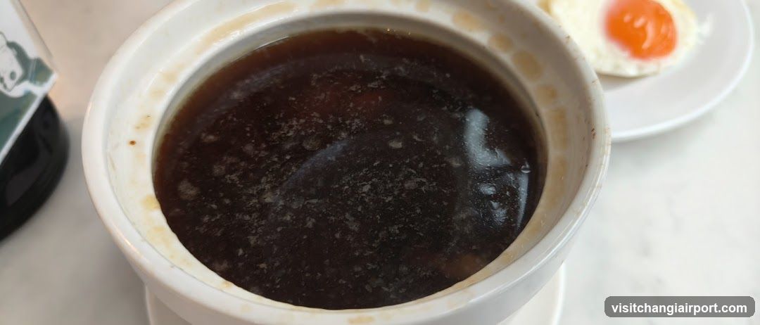 Bowl of Dark Soup with Fried Egg Side Dish