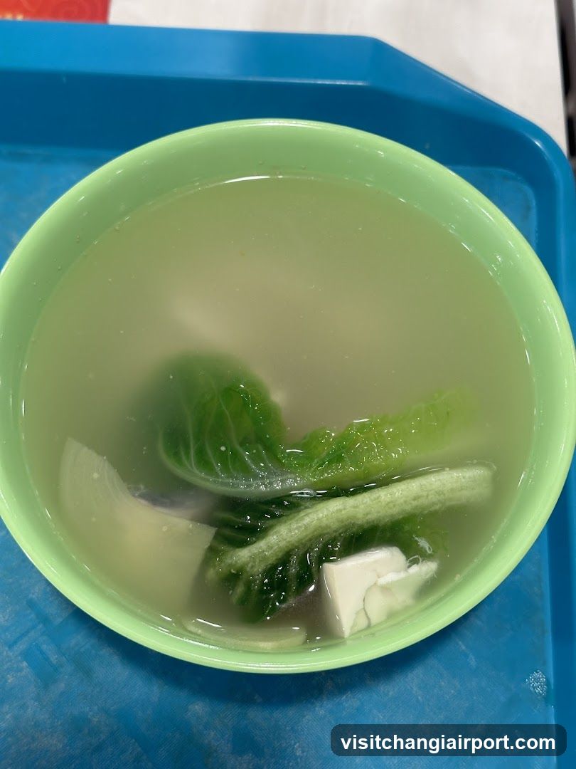 Bowl of clear soup with greens and tofu