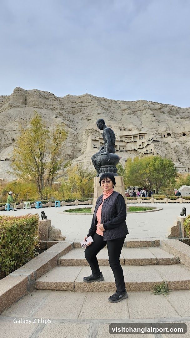 Woman posing in front of a statue and cave complex