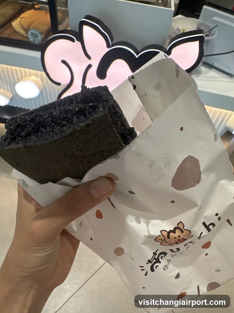 Hand holding a dark cake in branded paper bag