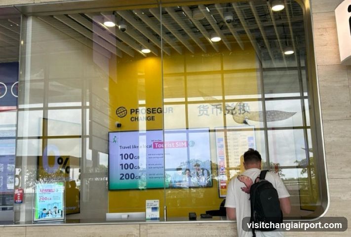 A storefront with glass windows displaying a yellow interior wall and signage reading 'PROSEGUR CHANGE' and Chinese characters for currency exchange. A digital screen shows travel SIM cards with prices like 100, 200, and 300. A person stands outside near the entrance.