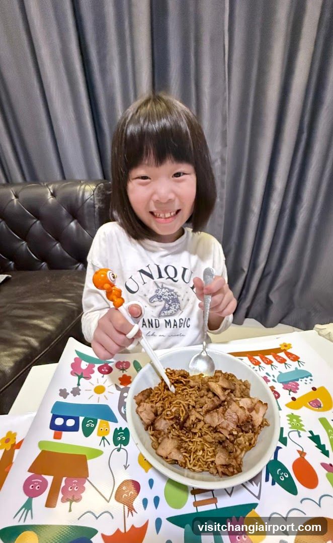 Child eating noodles with chopsticks and spoon